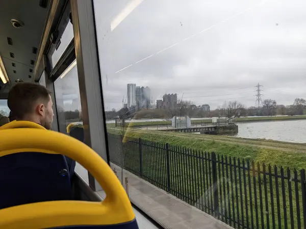 stock image London, UK - 03.01.2022: A male passenger looking out the window on the upper floor of a double-decker bus towards High Maynard Reservoir of Walthamstow Wetlands during the pandemic on a cloudy day