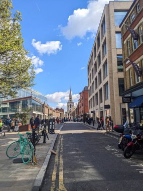 Londra, İngiltere - 04.03.2022: Spitalfields Market 'in dışındaki Brushfield Caddesi' nin kaldırımında yürüyen yayalar, Covid-19 sırasında arkasında İsa Kilisesi Spitalfields ile birlikte restoranlar ve dükkanlar var.