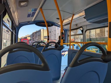 Londra, İngiltere - 04.09.2022: Çift katlı bir otobüsün üst katında oturan bir yolcu, tarihi bir mahallede, tırabzanları, stop düğmeleri ve görünürde bilgi panosu olan bir yolcu