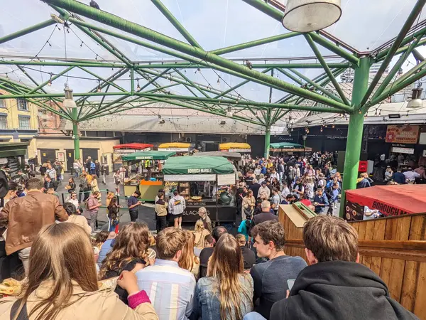 Londra, İngiltere - 05.07.2022: Borough Market Kitchen 'daki pazar tezgahlarından alışveriş yapan ve gezen ziyaretçiler, güneşli bir günde pandemik altında, merdivenlerde oturan insanlarla birlikte,