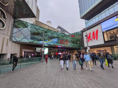 London, UK - 2023.02.11: Shoppers entering and leaving Westfield Stratford City via ground floor entrance on a cloudy day clipart