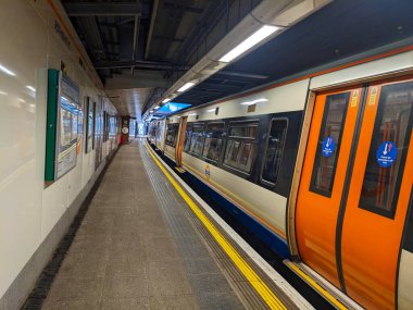 Londra, İngiltere - 2023.03.22: Bir Londra metro treni Rotherhithe İstasyonu 'nda boş bir platformda kapıları kapalı bir şekilde bekliyor