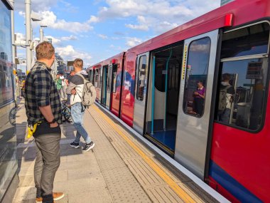 Londra, İngiltere - 2023.06.29: Docklands Light Railway treninin dışındaki platformda bekleyen yolcular Poplar İstasyonu 'ndaki tren arızası sırasında kapılar açıldı