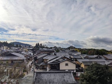 Kyoto, Japonya - 2023.12.16: Geleneksel Japon evleri ve yayalar arasında bulutlu mavi gökyüzünün altında yürüyen taş döşeli Ninenzaka 'nın görüntüsü