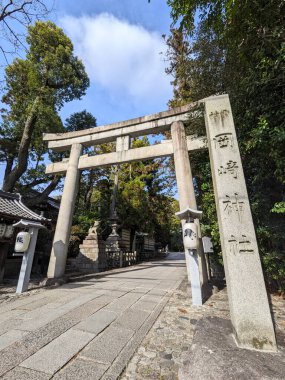 Kyoto, Japonya - 2023.12.18: Okazaki Tapınağı 'nın oymalı bir taş gövde kapısı, taştan fenerler ve güneşli mavi gökyüzünün altındaki heykellerin yanında Tavşanlar Tapınağı