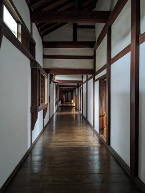 Himeji, Japonya - 12.19.2023: Himeji Kalesi 'nde turistler olmadan beyaz duvarlar, ahşap çatı, tavan, pencereler ve zeminin olduğu bir koridor içinde