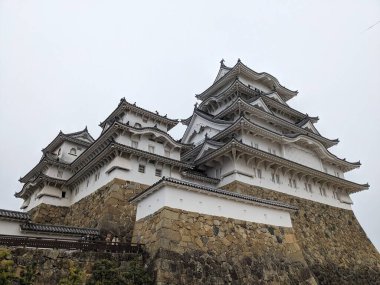 Himeji, Japonya - 12.19.2023: Himeji Şatosu 'nun yüksek taş duvarındaki Ana Kale cephesi