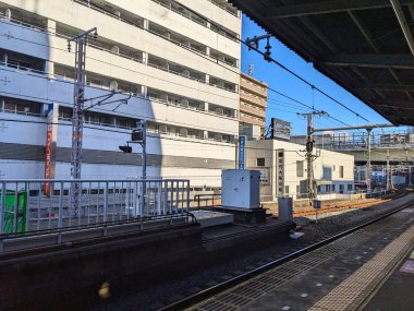 Osaka, Japonya - 12.21.2023: Modern binaların yanında, yolcu olmadan mavi gökyüzünün altında Temma İstasyonu 'ndaki platformun kenarına döşenmiş boş bir yan platform.