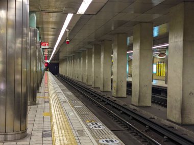 Osaka, Japonya - 01.01.2024: Tanimachi Yonchome İstasyonu 'ndaki boş bir Chuo Hattı platformu beton, metal sütunlar ve platformun kenarına kırmızı ışık ile döşenmiş sarı dokunmatik kaldırımlar