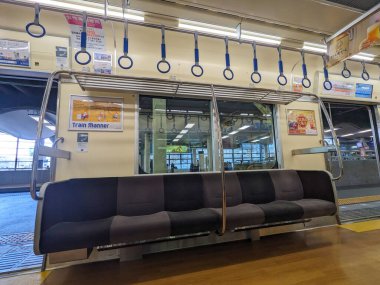 Osaka, Japonya - 01.01.2024: Nankai Demiryolu treninin içi boş koltuklar, asılmış tırabzanlar, bir pencere ve Namba İstasyonu Nankai 'de durduğunda reklam