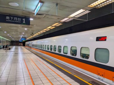 Taoyuan, Tayvan - 26.12.2023: Tayvan Yüksek Hız Treni platformunda yolcuları ve yolcuları beklerken durduğunda, Taoyuan İstasyonu 'nun güney platformunda oturan bir yolcu