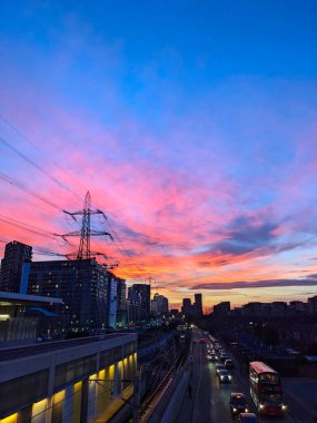 Londra, İngiltere - 02.01.2024: Özel Ev Elizabeth Hattı üzerinde pembe ve altın gece, arabalar ve kırmızı ışık önünde kuyruğa giren bir otobüs üzerinde parıldıyor 