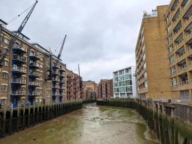 Londra, İngiltere - 05.13.2024: Yeni Concordia Rıhtımı 'ndaki tarihi rıhtımlar ve depoları Thames Nehri' nin alçak dalgalı sularda görünen çamur tabakalarına bakan vinçlerle dolu bir dizi tarihi liman kenarı ve depo