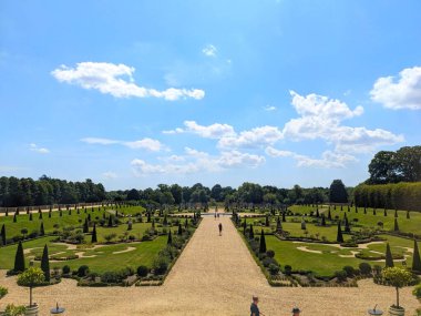 Londra, İngiltere - 07.19.2024: Hampton Court Palace 'daki iyi bakımlı Privy Garden' a ziyaretçiler açık mavi gökyüzü altında güneş ışığıyla yürüyorlar