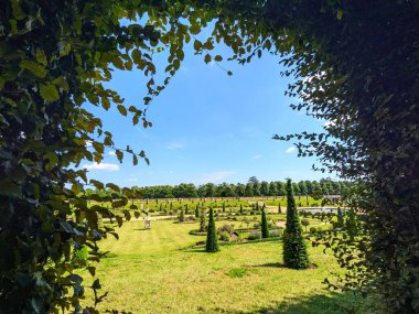 Londra, İngiltere - 07.19.2024: Hampton Court Palace 'daki iyi bakımlı Privy Garden manzarası açık mavi bir gökyüzü altında çiçek tünelinden bir yaprak çerçevesi ile
