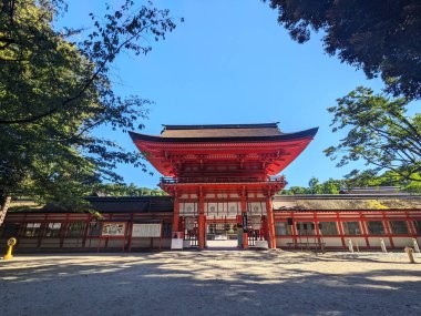 Kyoto, Japonya - 08.08.2024 Shimogamo Tapınağı girişi Japon çatısı altında kırmızı ahşap bir yapı ve açık mavi gökyüzü altında iki koridor