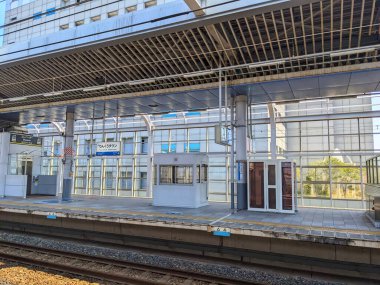 Rinku Town, Japan - 08.13.2024: Nankai Electric Railway and JR West platforms serving side by side on one of the island platforms alongside tracks at Rinku-town Station with sunlight in summer clipart