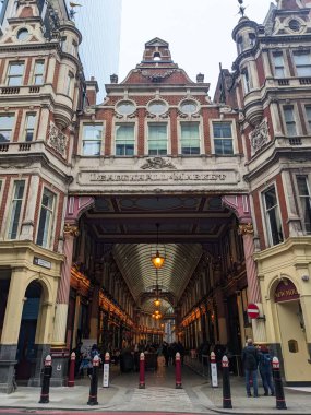 Londra, İngiltere - 26.10.2024: Leadenhall Market Gracechurch Caddesi girişi kırmızı tuğlalar, bulutlu bir gökyüzü altında mermer heykel ve atari salonuna doğru yürüyen ve fotoğraf çeken turistler