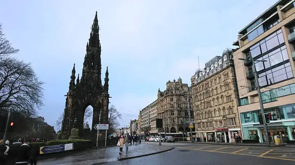 Edinburgh, İngiltere - 2.10.2018: Princes Caddesi 'ndeki Princes Caddesi' ndeki Scott Anıtı 'nda tarihi binaların yanında yürüyen yayalar ve salgından önce bulutlu bir gökyüzü altındaki dükkanları dönüştürdü