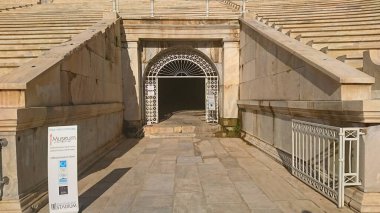 Athens, Greece - 29.3.2018: Entrance to the Museum of Panathenaic Stadium in the Atrium Hall via an arched doorway and a tunnel under marble steps without tourists under sunlight before the pandemic clipart