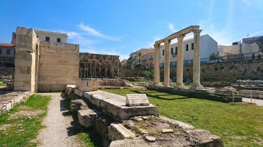 Atina, Yunanistan - 30.3.2018: Roma Agora 'da kışın hiç turist bulunmayan salgından önce güneşli mavi gökyüzünün altındaki çimlerin arasında ayakta duran sütunlar ve kırık duvarlar