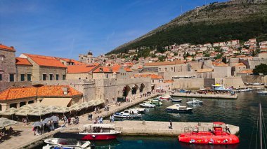 Dubrovnik, Hırvatistan - 14 Nisan 2018: Antik taş binalar ve güneşli bir günün keyfini çıkaran turistlerle dolu açık mavi gökyüzüyle çevrili pitoresk Eski Kent limanı