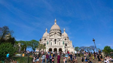Paris, Fransa - 21 Nisan 2018: Sacre-Coeur Bazilikası 'nda turistlerin açık mavi gökyüzünün altında basamakları tırmandığı, mimari güzelliği ve Montmartre' nin canlı atmosferini gösteren canlı bir sahne