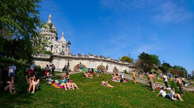 Paris, Fransa - 21 Nisan 2018: Sacre-Coeur Bazilikası 'nın basamaklarında güneşli bir günün keyfini çıkaran insanlar, oturma grupları çimlerin üzerinde dinleniyor ve baharda yukarıdaki açık mavi gökyüzü