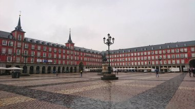 Madrid, İspanya - 28 Mayıs 2018: Plaza Belediye Başkanı ve Felipe III Heykeli ikonik kırmızı binaları ve kaldırımlarıyla bulutlu gökyüzünün altında sessiz bir atmosfer sergiliyor.