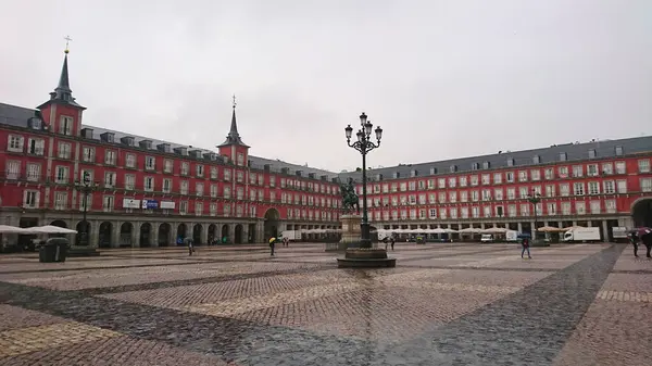 Madrid, İspanya - 28 Mayıs 2018: Plaza Belediye Başkanı ve Felipe III Heykeli ikonik kırmızı binaları ve kaldırımlarıyla bulutlu gökyüzünün altında sessiz bir atmosfer sergiliyor.