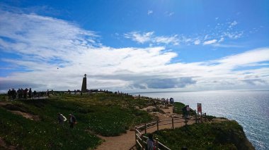 Cabo da Roca, Portekiz - 3 Haziran 2018: Cabo da Roca kıyı şeridinin muhteşem manzarası ziyaretçiler manzarayı keşfediyor ve bir haçı olan bir anıt parlak mavi bir gökyüzünün altında duruyor