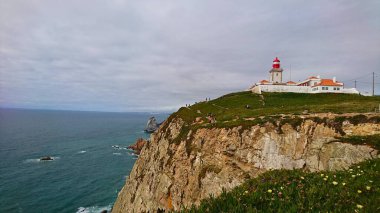 Cabo da Roca, Portekiz - 3 Haziran 2018: Cabo da Roca uçurumlarından doğal güzelliği ve kıyı sükunetini gösteren bir deniz feneri ile manzara