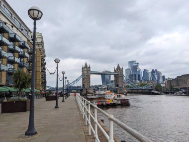 Londra, İngiltere - 05.13.2024: Butlers Rıhtımı üzerinde Thames nehrinin kenarına demirlemiş bir restoran ve tekneler boyunca uzanan bir patika.