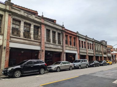 Taipei, Tayvan - 11.23.2022: Bulutlu bir gökyüzü altındaki salgın sırasında Bopiliao Tarihi Bloğu 'ndaki boş bir sokakta kırmızı tuğlalı sütunlar, beton yapılar ve kırmızı fayanslar bulunan veranda boyunca park edilmiş arabalar