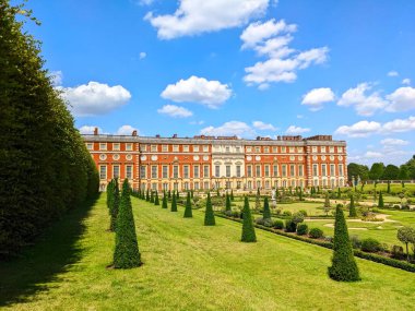 Londra, İngiltere - 07.19.2024: Önünde Privy Garden ile Güney Cephesi ve solunda Hampton Court Palace 'da açık mavi gökyüzünün altında bir bitki tüneli var.