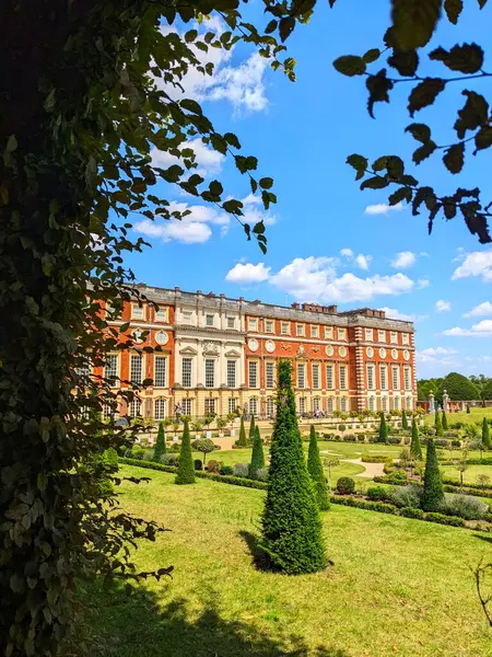 Londra, İngiltere - 07.19.2024: Hampton Court Palace 'daki Privy Garden ile Güney Cephesi, açık mavi gökyüzü altında güneş ışığı ve bulutlar altında çiçek tüneli manzarası