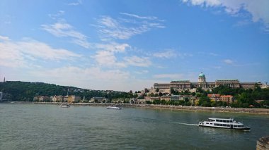 Budapeşte, Macaristan - 5 Haziran 2018: Tuna Nehri 'ne tepeden bakan Kraliyet Sarayı ve açık mavi bir gökyüzü altında yüzen teknelerle Buda tarafının manzarası