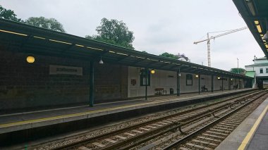 Viyana, Avusturya - 7 Haziran 2018: Schonbrunn tren istasyonu platformu bulutlu bir gökyüzü altında görünen tren rayları altında sakin bir seyahat ve geçiş atmosferi yaratıyor