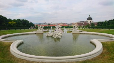Viyana, Avusturya - 7 Haziran 2018: Schloss Belvedere bahçelerindeki süslü fıskiyelerin ve heykellerin sakin manzarası bulutlu bir günde ziyaretçilerin yemyeşil havanın keyfini çıkarmaları