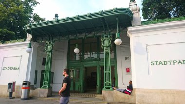 Viyana, Avusturya - 7 Haziran 2018: Stadtpark 'ın büyüleyici girişi karmaşık Art Nouveau tasarımı içeriyor, bir erkek merdivenlerde yürürken bir kadın canlı atmosferin tadını çıkarıyor