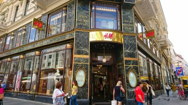 Viyana, Avusturya - 8 Haziran 2018: Güneşli bir günde perakende terapisine katılan, karmaşık altın ve yeşil mermerlerle süslenmiş H ve M mağazasının dışındaki hareketli bir sahne
