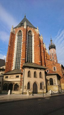 Krakow, Polonya - 9 Haziran 2018: St. Marys Bazilikası 'nın göz kamaştırıcı cephesi, açık mavi gökyüzünün altında yükselen tuğlalar, ziyaretçilerin ilgisini çeken Gotik mimarinin bir simgesi.