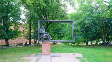 Krakow, Polonya - 9 Haziran 2018: Jan Matejko heykeli, güneşli bir öğleden sonra yemyeşil bir parkta oturan, büyük bir çerçevede çerçevelenmiş, oturan bir figürden oluşur.