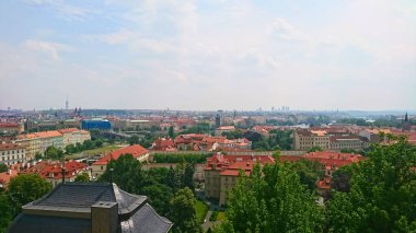 Prag, Çek Cumhuriyeti - 11 Haziran 2018: Kırmızı çatılı binaların panoramik manzarası ve tarihi mimarisi olan yemyeşil alanlar ve salgından önce sakin bir gökyüzü