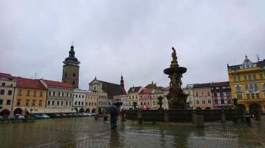 Ceske Budejovice, Çek Cumhuriyeti - 12 Haziran 2018: Premysl Otakar II Meydanı 'ndaki Samsonova Çeşmesi' nde yağmurlu bir günde canlı binalar ve görünür bir saat kulesi