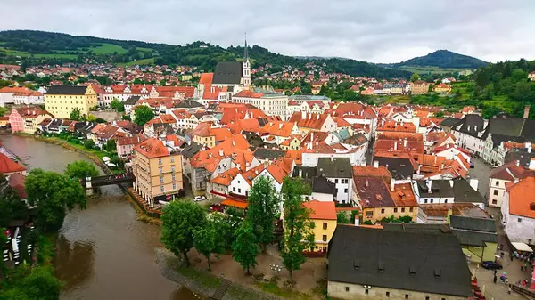 Cesky Krumlov, Çek Cumhuriyeti - 12 Haziran 2018: Renkli binaları ve Vltava Nehri boyunca kırmızı çatıları olan ortaçağ kasabasının manzarası bulutlu bir günde canlı bir atmosfer yaratıyor