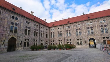 Münih, Almanya - 6.15.2018: Residenz 'in avlusu gün içinde bulutlu gökyüzü ve terasotta çatılarının zeminine karşı karmaşık mimari ve canlı saksılar sergiliyor