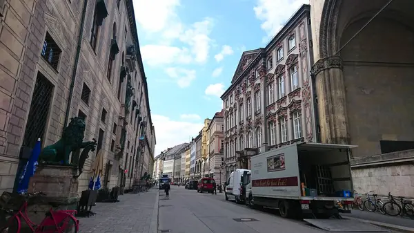 Münih, Almanya - 6.15.2018: Feldherrnhalle 'in yanında sakin bir sokak, karmaşık mimari sergilenen ve parçalı bulutlu bir gökyüzünün altında bisikletlerin arasına park edilmiş bir teslimat kamyonu