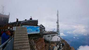 Zugspitze, Almanya - 6.17.2018: Almanya 'nın en yüksek zirvesinden panoramik manzaranın keyfini çıkaran ziyaretçiler ve arkada sisle örtülü Munchner Haus