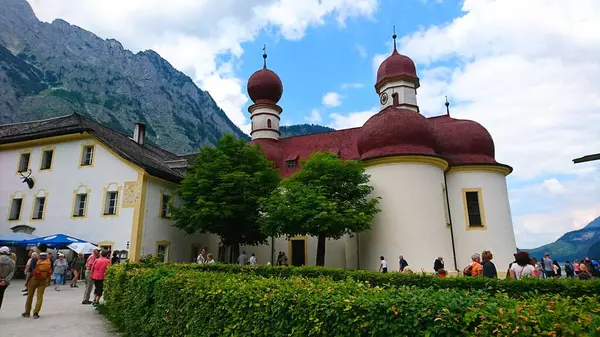 Konigssee, Almanya - 6.16.2018: Ziyaretçiler, ikonik St. Bartholomews Kilisesi 'nin dış yüzeyini keşfediyor.